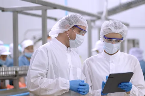Engineers control quanlity and process of production by application on tablet, discussing project work 