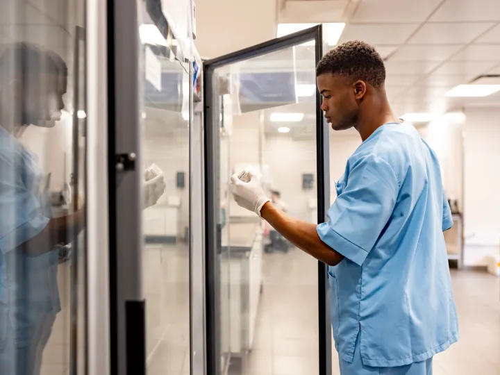 Man at pharmacy fridge inspecting product