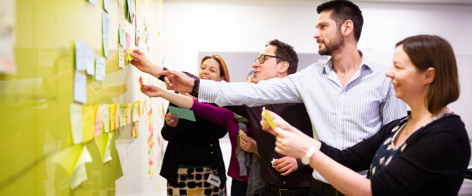 team working together to put sticky notes on a board