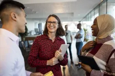 Lady holding a notepad smiles at two other people.