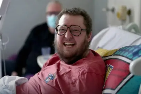Leukaemia patient Oscar Murphy in a hospital bed, smiling