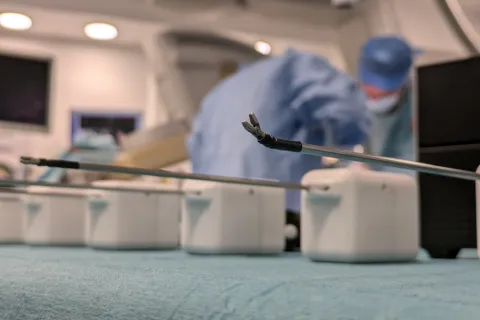 close up of surgical tools, with operating room in the background