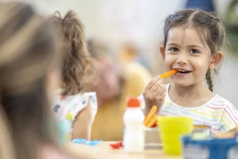 young girl eating carrot smiling