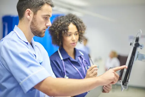 male and female clinicians at a digital portal in a hospital setting