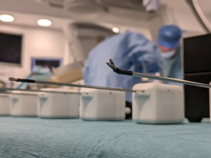 close up of surgical tools, with operating room in the background