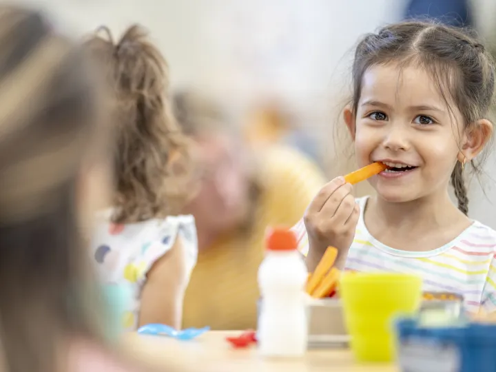 young girl eating carrot smiling