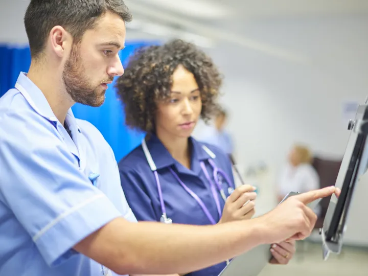 male and female clinicians at a digital portal in a hospital setting